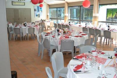 Piscine intérieure visible à travers une baie vitrée entourée de murs recouverts de plantes grimpantes, avec des tables…