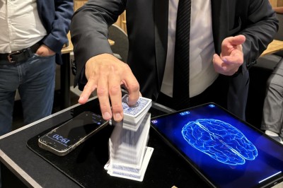 Un homme en costume verse une boisson depuis une tablette numérique dans un verre, illustrant un effet magique.