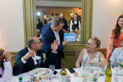 Un homme en costume verse une boisson depuis une tablette numérique dans un verre, illustrant un effet magique.