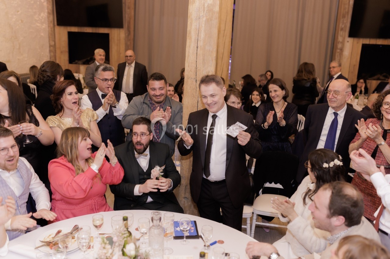 Un groupe de personnes applaudissant autour d'une table lors d'un événement festif en intérieur.