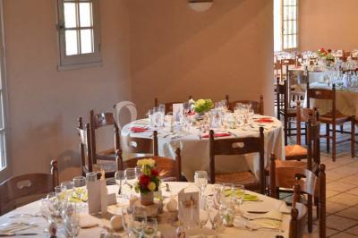 Table dressée avec nappes rouges, serviettes pliées, verres et assiettes, dans une salle lumineuse avec un serveur en…