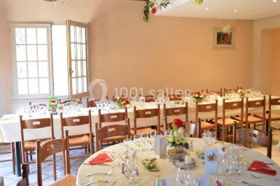 Table dressée avec nappes rouges, serviettes pliées, verres et assiettes, dans une salle lumineuse avec un serveur en…