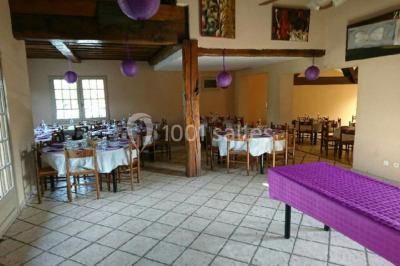 Table dressée avec nappes rouges, serviettes pliées, verres et assiettes, dans une salle lumineuse avec un serveur en…