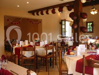 Table dressée avec nappes rouges, serviettes pliées, verres et assiettes, dans une salle lumineuse avec un serveur en…