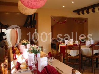 Table dressée avec nappes rouges, serviettes pliées, verres et assiettes, dans une salle lumineuse avec un serveur en…