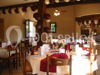 Table dressée avec nappes rouges, serviettes pliées, verres et assiettes, dans une salle lumineuse avec un serveur en…
