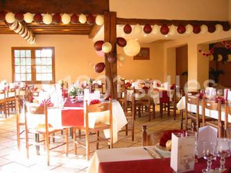 Table dressée avec nappes rouges, serviettes pliées, verres et assiettes, dans une salle lumineuse avec un serveur en…