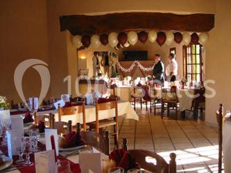 Salle décorée pour une réception avec tables dressées, ballons suspendus et deux personnes près d'un buffet.
