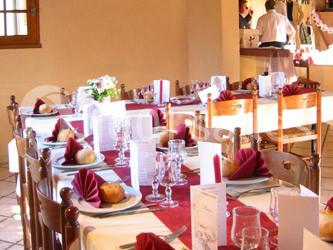 Table dressée avec nappes rouges, serviettes pliées, verres et assiettes, dans une salle lumineuse avec un serveur en…