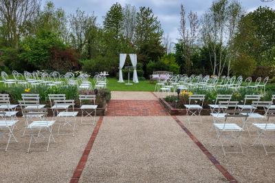 Miniature Location salle Neufchâtel-en-Bray (Seine-Maritime) - Le Cellier du Val Boury #6 Jardin fleuri avec des plantes variées devant une maison en briques et toit en tuiles, entourée d'arbres.