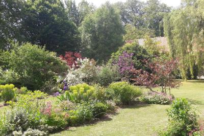 Miniature Location salle Neufchâtel-en-Bray (Seine-Maritime) - Le Cellier du Val Boury #20 Jardin fleuri avec des plantes variées devant une maison en briques et toit en tuiles, entourée d'arbres.
