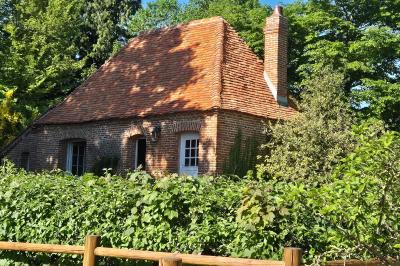 Miniature Location salle Neufchâtel-en-Bray (Seine-Maritime) - Le Cellier du Val Boury #4 Jardin fleuri avec des plantes variées devant une maison en briques et toit en tuiles, entourée d'arbres.