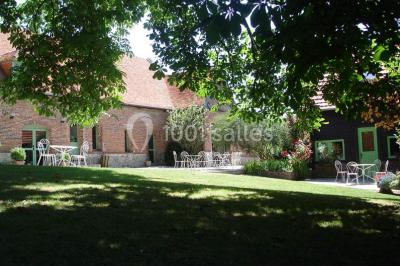 Miniature Location salle Neufchâtel-en-Bray (Seine-Maritime) - Le Cellier du Val Boury #33 Jardin fleuri avec des plantes variées devant une maison en briques et toit en tuiles, entourée d'arbres.