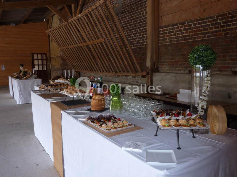 Buffet avec des plateaux de canapés, verrines et pains disposés dans une salle au style rustique avec murs en briques.