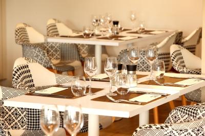 Salle de casino avec machines à sous lumineuses, écrans de jeux interactifs et un bar en arrière-plan.