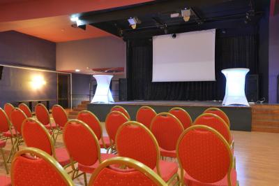 Salle de casino avec machines à sous lumineuses, écrans de jeux interactifs et un bar en arrière-plan.