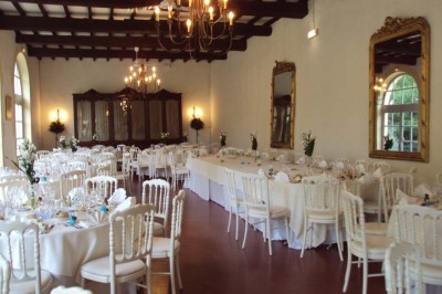 Un couple en tenue de cérémonie est transporté dans une calèche tirée par des chevaux sur un chemin bordé d'arbres.