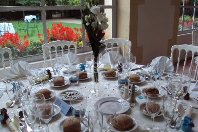 Un couple en tenue de cérémonie est transporté dans une calèche tirée par des chevaux sur un chemin bordé d'arbres.