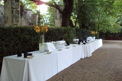 Un couple en tenue de cérémonie est transporté dans une calèche tirée par des chevaux sur un chemin bordé d'arbres.