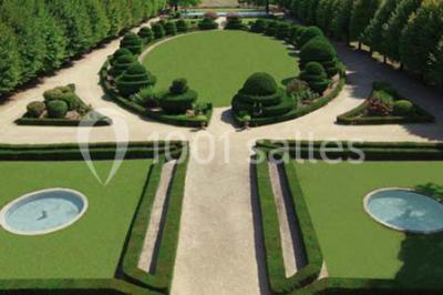 Un couple en tenue de cérémonie est transporté dans une calèche tirée par des chevaux sur un chemin bordé d'arbres.