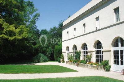 Un couple en tenue de cérémonie est transporté dans une calèche tirée par des chevaux sur un chemin bordé d'arbres.