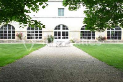 Un couple en tenue de cérémonie est transporté dans une calèche tirée par des chevaux sur un chemin bordé d'arbres.