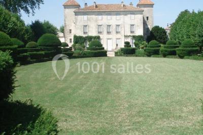 Un couple en tenue de cérémonie est transporté dans une calèche tirée par des chevaux sur un chemin bordé d'arbres.
