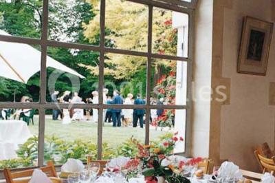 Un couple en tenue de cérémonie est transporté dans une calèche tirée par des chevaux sur un chemin bordé d'arbres.