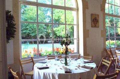 Un couple en tenue de cérémonie est transporté dans une calèche tirée par des chevaux sur un chemin bordé d'arbres.