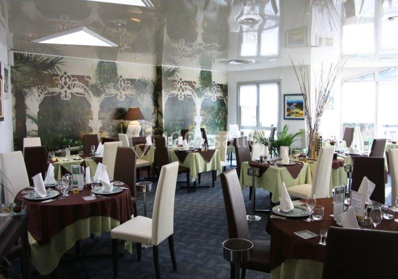 Salle de restaurant élégante avec tables dressées, nappes colorées, chaises modernes et décoration végétale.