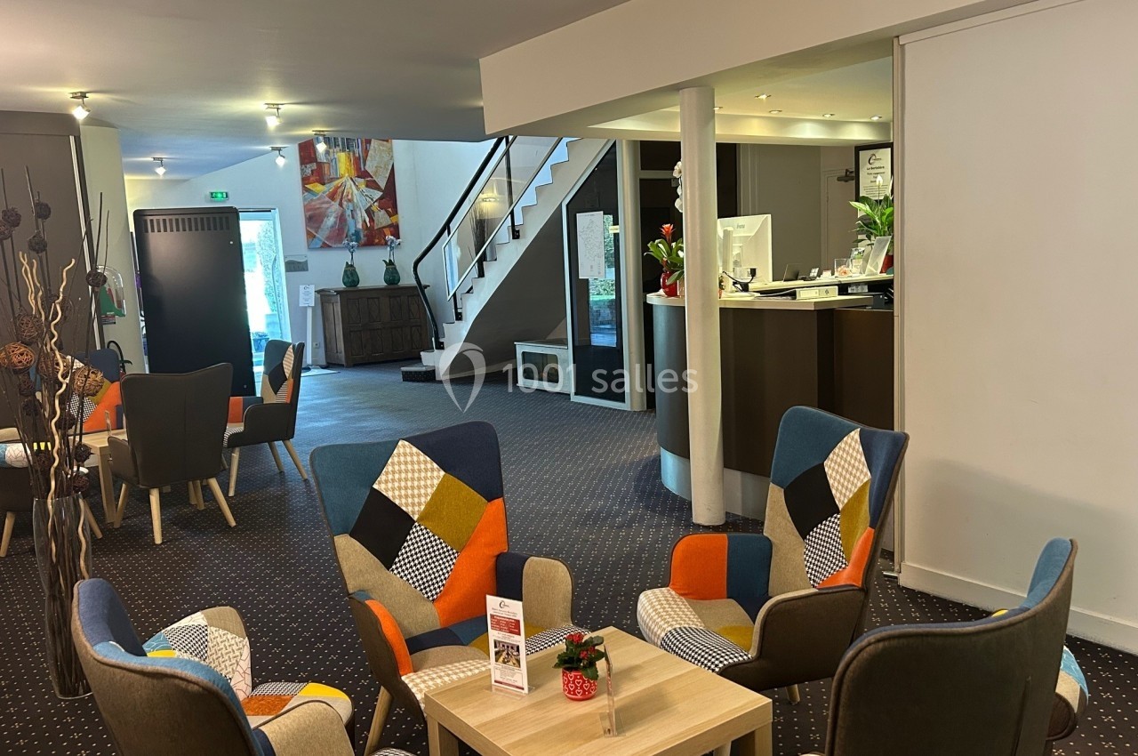 Espace d'accueil moderne avec fauteuils colorés, table basse et comptoir de réception en arrière-plan.