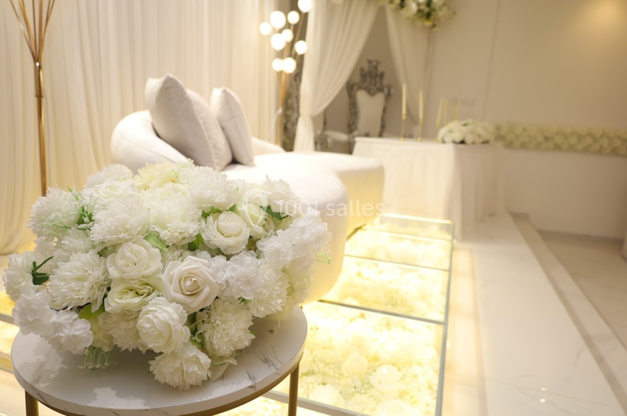 Bouquet de fleurs blanches sur une table ronde devant un salon décoré dans des tons clairs et élégants.
