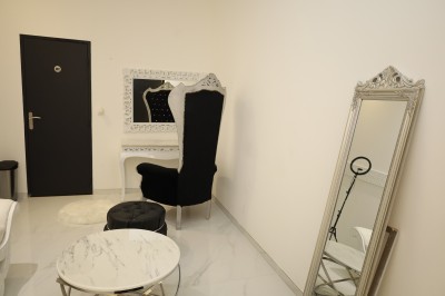 Salle lumineuse avec table drapée de blanc, décorée de fleurs et bougies, donnant sur un extérieur arboré.