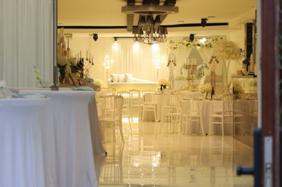 Miniature Location salle Saint-Priest (Rhône) - Kesh Réception #2 Salle lumineuse avec table drapée de blanc, décorée de fleurs et bougies, donnant sur un extérieur arboré.