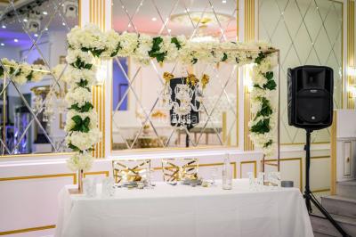 Table dressée avec une assiette blanche, un cadeau doré, une serviette beige nouée et des macarons en décoration.