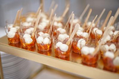 Table dressée avec une assiette blanche, un cadeau doré, une serviette beige nouée et des macarons en décoration.