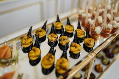 Table dressée avec une assiette blanche, un cadeau doré, une serviette beige nouée et des macarons en décoration.