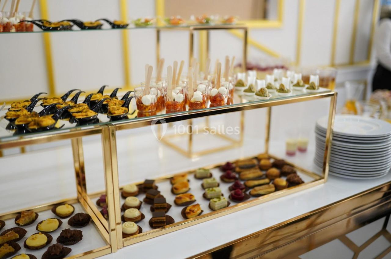 Présentoir doré avec une variété de bouchées salées et sucrées disposées sur deux étages.
