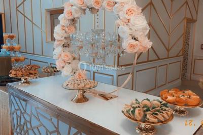 Table dressée avec une assiette blanche, un cadeau doré, une serviette beige nouée et des macarons en décoration.
