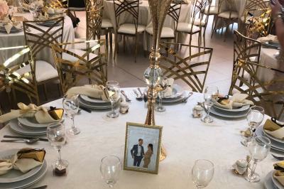 Table dressée avec une assiette blanche, un cadeau doré, une serviette beige nouée et des macarons en décoration.