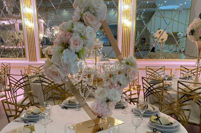 Table dressée avec une assiette blanche, un cadeau doré, une serviette beige nouée et des macarons en décoration.