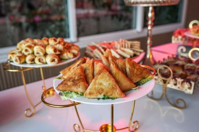 Table dressée avec une assiette blanche, un cadeau doré, une serviette beige nouée et des macarons en décoration.