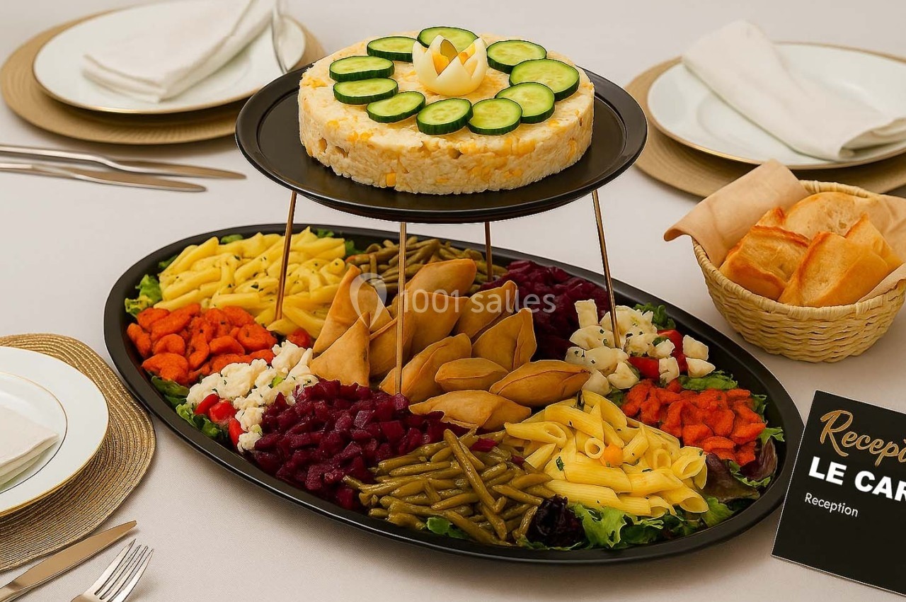 Plateau de buffet avec assortiment de légumes, pâtes, samoussas et un gâteau décoré de rondelles de concombre.