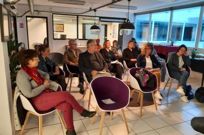 Salle de classe vide avec des tables et chaises jaunes alignées, éclairée par des fenêtres sur les côtés.