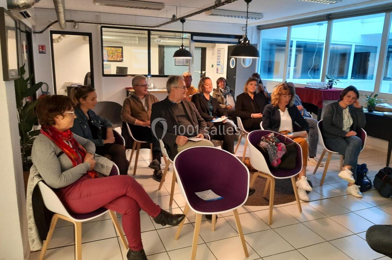 Un groupe de personnes assises dans une salle moderne, participant à une réunion ou une présentation.