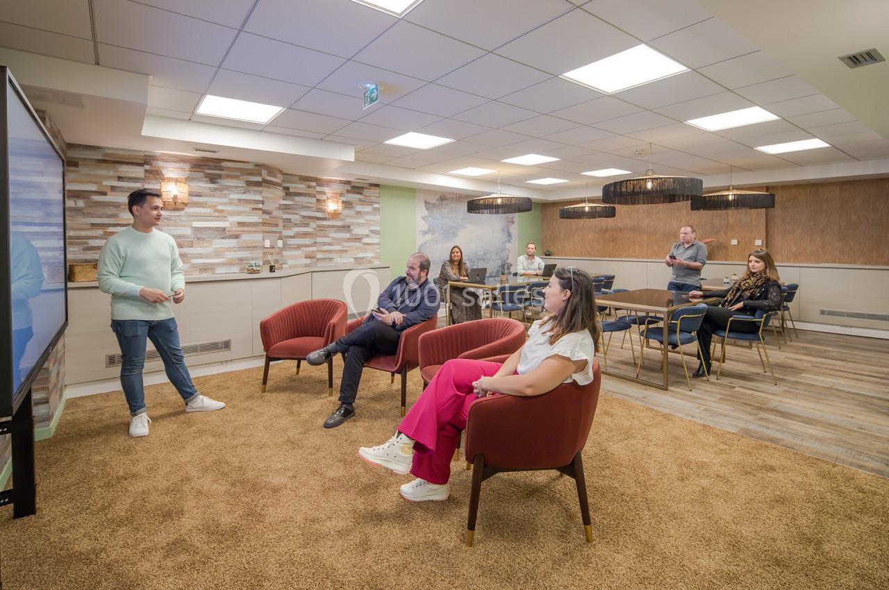 Un homme présente devant un petit groupe de personnes assises dans une salle de réunion moderne.