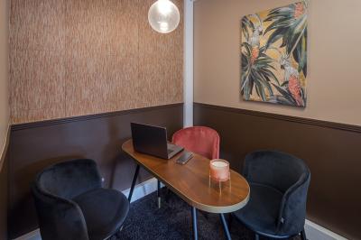 Salle moderne avec tables noires, chaises bleues, étagères murales, et écran mural dans un espace lumineux et décoré.