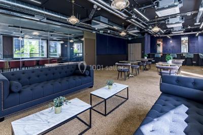 Salle de réunion moderne avec table en verre, chaises violettes, écran mural et fenêtres laissant entrer la lumière…