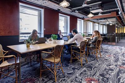 Salle de réunion moderne avec table en verre, chaises violettes, écran mural et fenêtres laissant entrer la lumière…