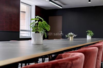 Salle de réunion moderne avec table en verre, chaises violettes, écran mural et fenêtres laissant entrer la lumière…